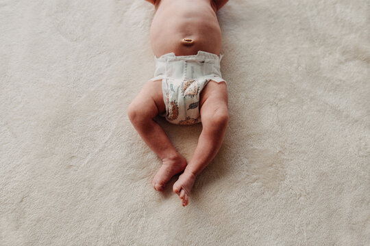 Close up of newborn belly button white diaper legs and feet