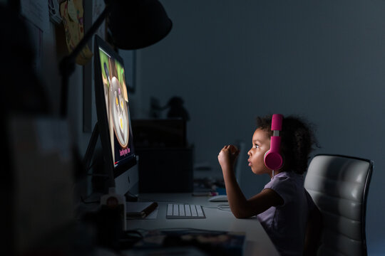 Young girl with headphones using computer at home - Powered by Adobe
