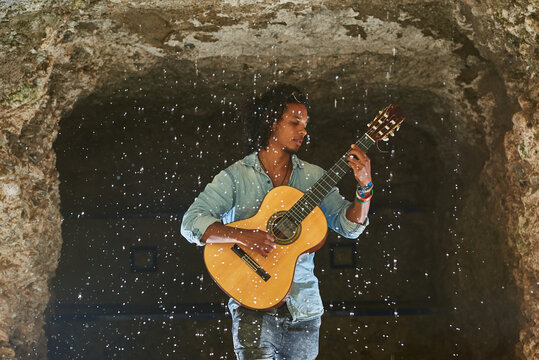 Musician with classical guitar playing in a cave.
