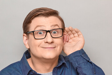 Portrait of happy man placing hand near ear and eavesdropping