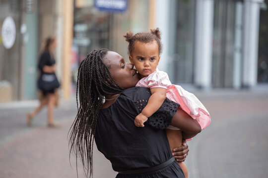 A black mother cuddles her daughter in the city