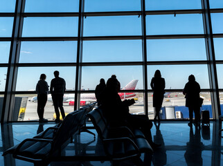 Silhouettes of passengers at the airport Vnukovo in the waiting hall against the background of the airfield and aircraft.