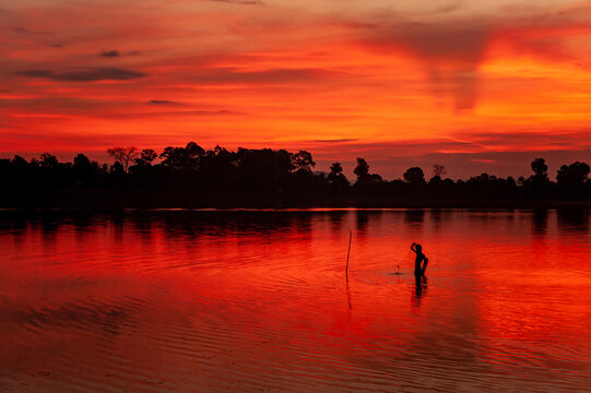 Early morning fisherman setting nets at sunrise in Sra Srang, Siem Reap, Cambodia. Angkorian bathing pool.