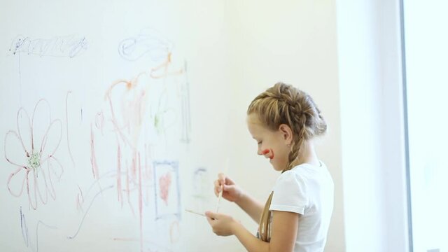 A little girl paints on the walls. The father scolds the child for the damaged wallpaper.