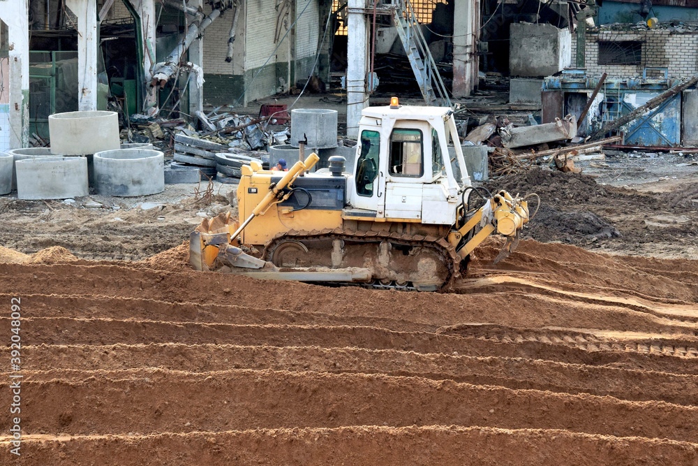 Wall mural bulldozer on construction site job of burying the old building