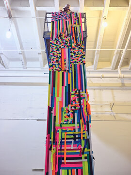 Artist installs large colorful tapestry off a scissor lift.