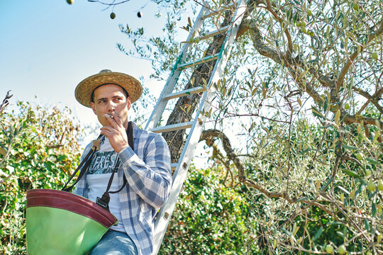 farmer smokes a cigarette sitting on the stairs taking a break - Powered by Adobe
