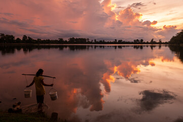 SRA SRANG,ANGKOR PARK, SIEM REAP, CAMBODIA - 14 August 2011: Local lady collects water in buckets over the shoulder for her garden from angkorian bathing pool.