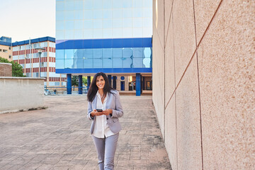 Business woman walking with mobile phone in hand.