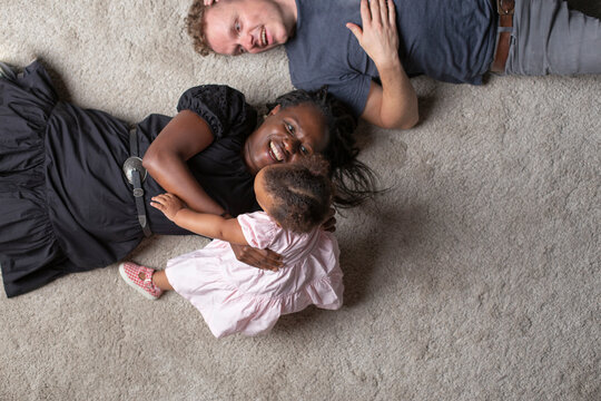 A young interracial couple playing with their young daughter