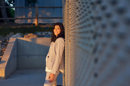Young woman leaning on the wall looking at camera.