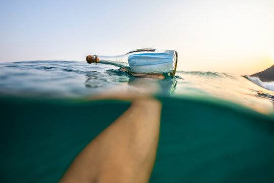 Holding a Covid-19 surgical face mask inside a glass bottle in the sea