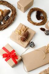Eco-friendly Christmas decor: gift boxes Packed in brown Kraft paper, natural decorations - wreath, pine on white background. Zero Waste holiday packing concept, handmade gifts package