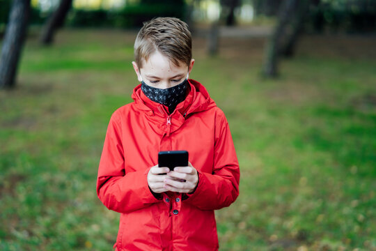 boy in red jacket playing with his smartphone