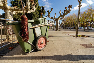 Street sweeper cart with broom left in a plaza in the autumn sun in Cambre Spain