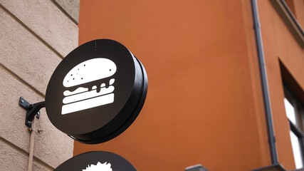 Circle black burger sign on wall behind glass