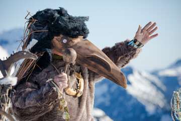 First Nations person dressed in Ravens mask preforms a ceremony.