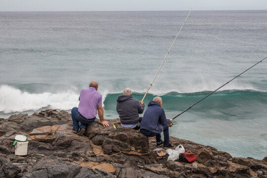 FUERTEVENTURA, SPAIN - FEBRUARY 15, 2018: Men fishing on the rocks in Puertito de Los Molinos, Canary Islands, Spain.