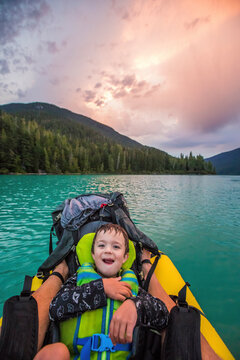 Young boy smiles, laughs during father son paddling trip.