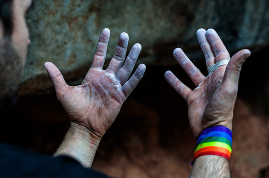 Hands and fingers of a climber with the gay pride bracelet, after finishing the climb.