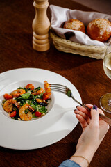 Fresh salad plate with shrimp, tomato and mixed greens on wooden background close up. Healthy food. Clean eating.