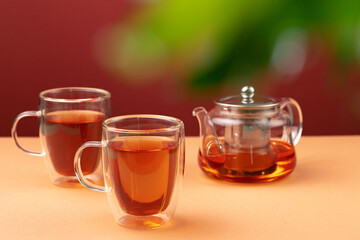 Glass teapot and two glass cups with tea
