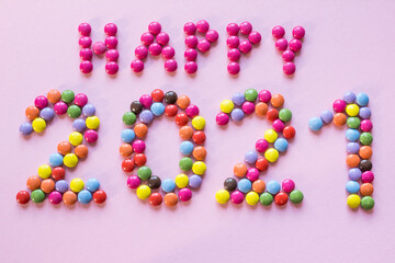 Happy New Year 2021 pink background with colorful chocolate candies
