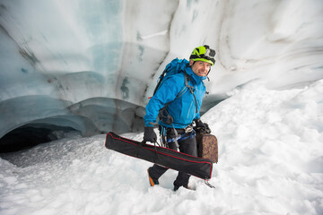 Scientist carries gear out of a glacier cave, British Columbia, Canada