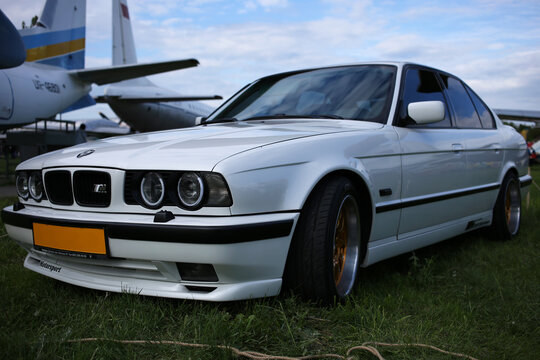 A rare, white BMW E34 m5 car with xenon headlights at an exhibition at the airport.