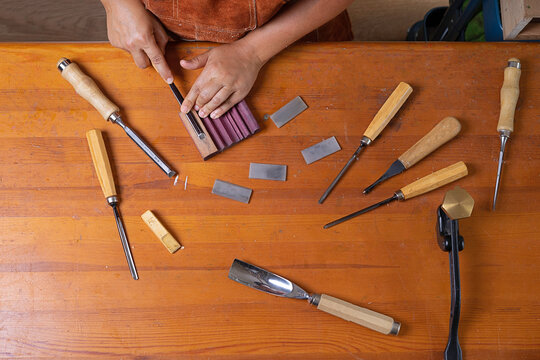 craftswoman sharpens a tool with an stone