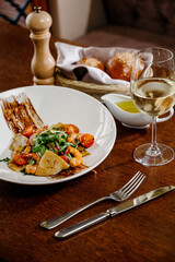 Fresh salad plate with shrimp, tomato and mixed greens on wooden background close up. Healthy food. Clean eating.