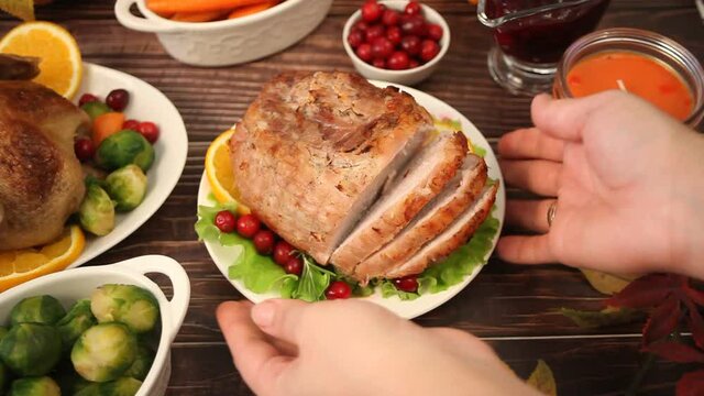 Woman hand put on the table traditional sliced honey glazed ham for festive Christmas or Thanksgiving day.