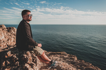 Young man looking out over ocean at sunset in Portugal in summer