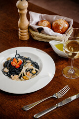 Black spaghetti. Spicy Black seafood pasta with squid with basil on wooden table.