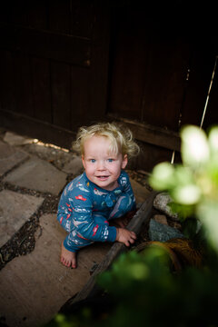 Two Year Old Smiling & Crouching in Yard Wearing Pajamas