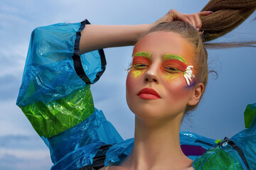 Creative fashionable beauty portrait of a beautiful young woman with long hair in a blue raincoat...