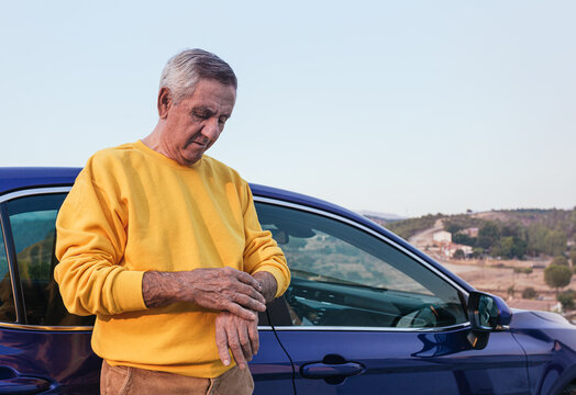Aged traveler checking time near car