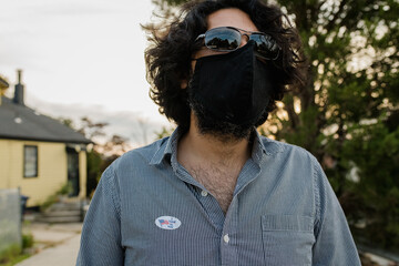 Man wearing protective face mask and I voted by mail sticker