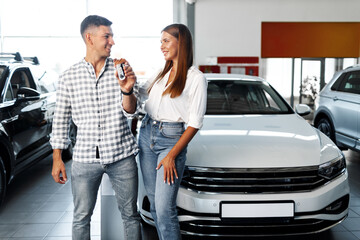 Young happy couple just bought a new car in a dealership