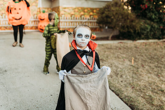 School aged boy dressed as Dracula Trick-or-Treating during Halloween