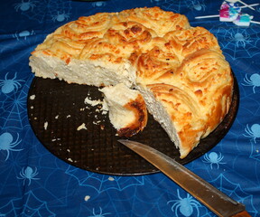 Pie with cheese from yeast dough. A piece has already been cut off with a knife.