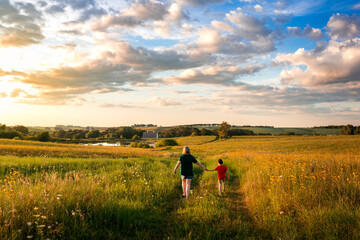 mother and son walking through a field of flowers on a rural farm