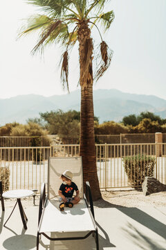 Young toddler boy with a mask on sitting by pool in Palm Springs