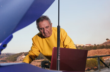 Senior man with laptop fixing car
