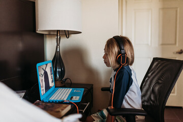School age boy distance learning in hotel room during pandemic