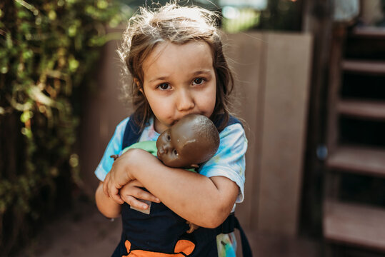 Close up of young girl cuddling with favorite baby doll outside