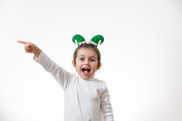 The girl with the hoop in the form of an elf hat on her head points her finger to the side.