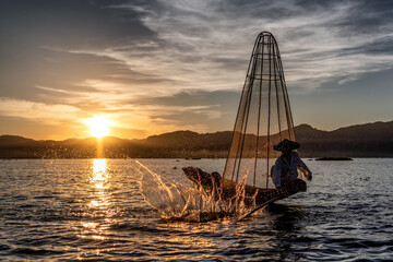Inle Lake, Myanmar - 3 December 2017 Fisherman slapping water to scare fish into his prelaid net.