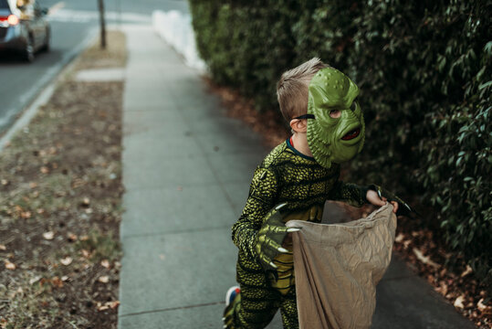 School aged boy dressed as monster Trick-or-Treating during Halloween