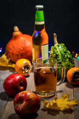Glass of apple cider with apples, pumpkins and persimmon on wooden table
